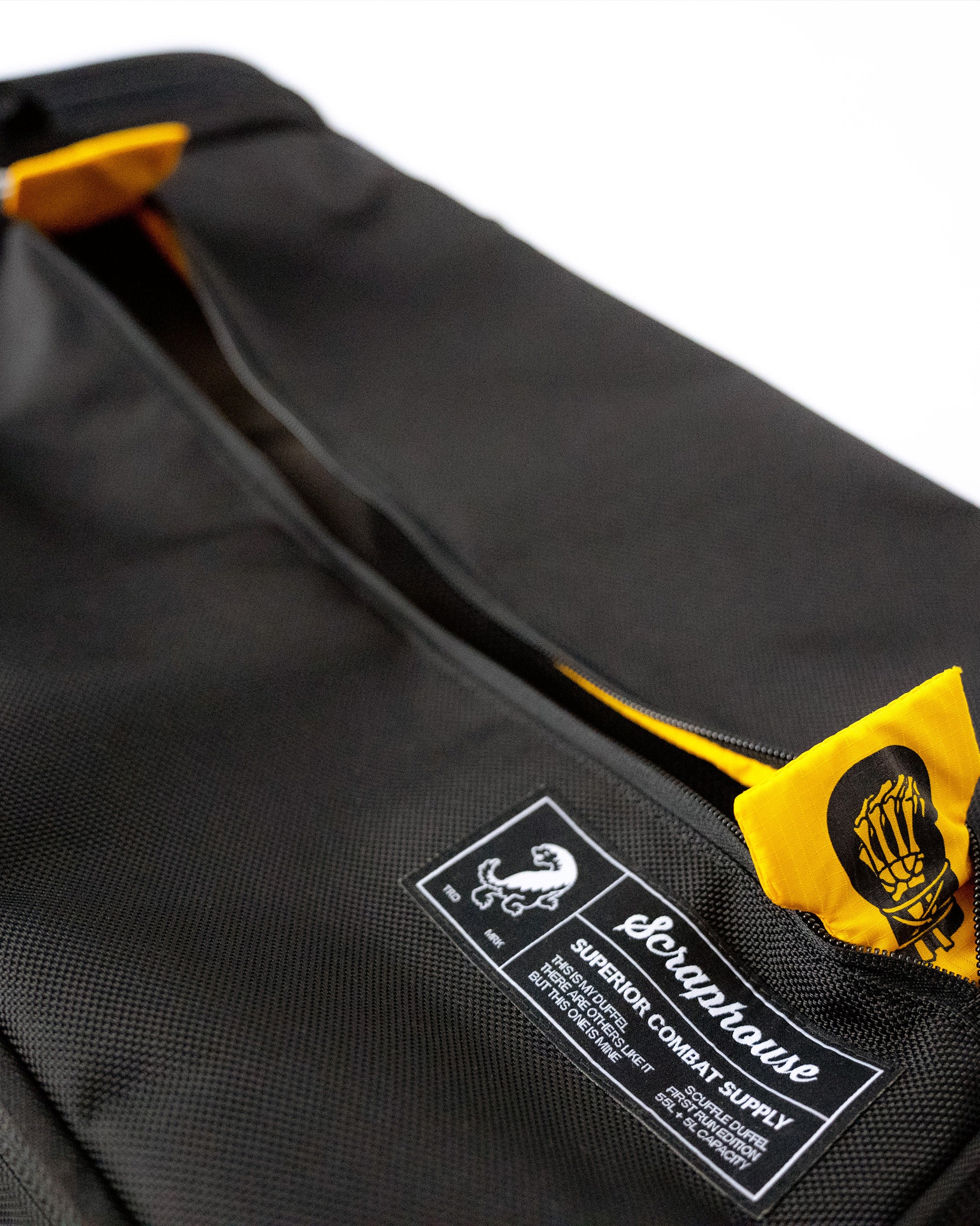 Woven Scraphouse label and zippered ventilation panel on the duffle's ballistic nylon shell