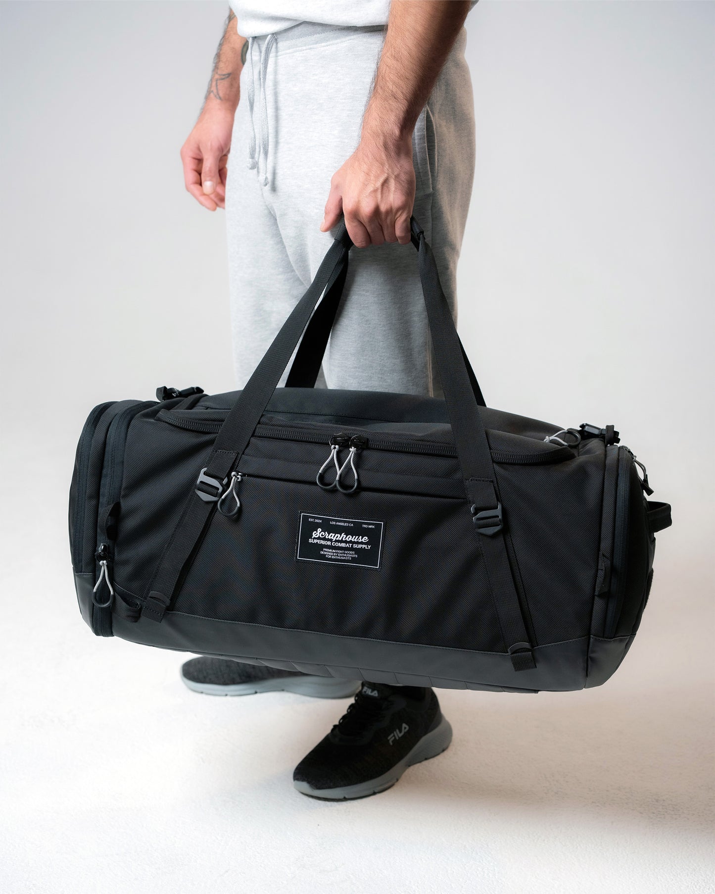 Athlete carrying the Scuffle Duffle by its reinforced top handles, shown for scale
