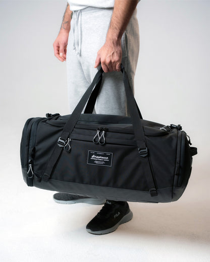Athlete carrying the Scuffle Duffle by its reinforced top handles, shown for scale
