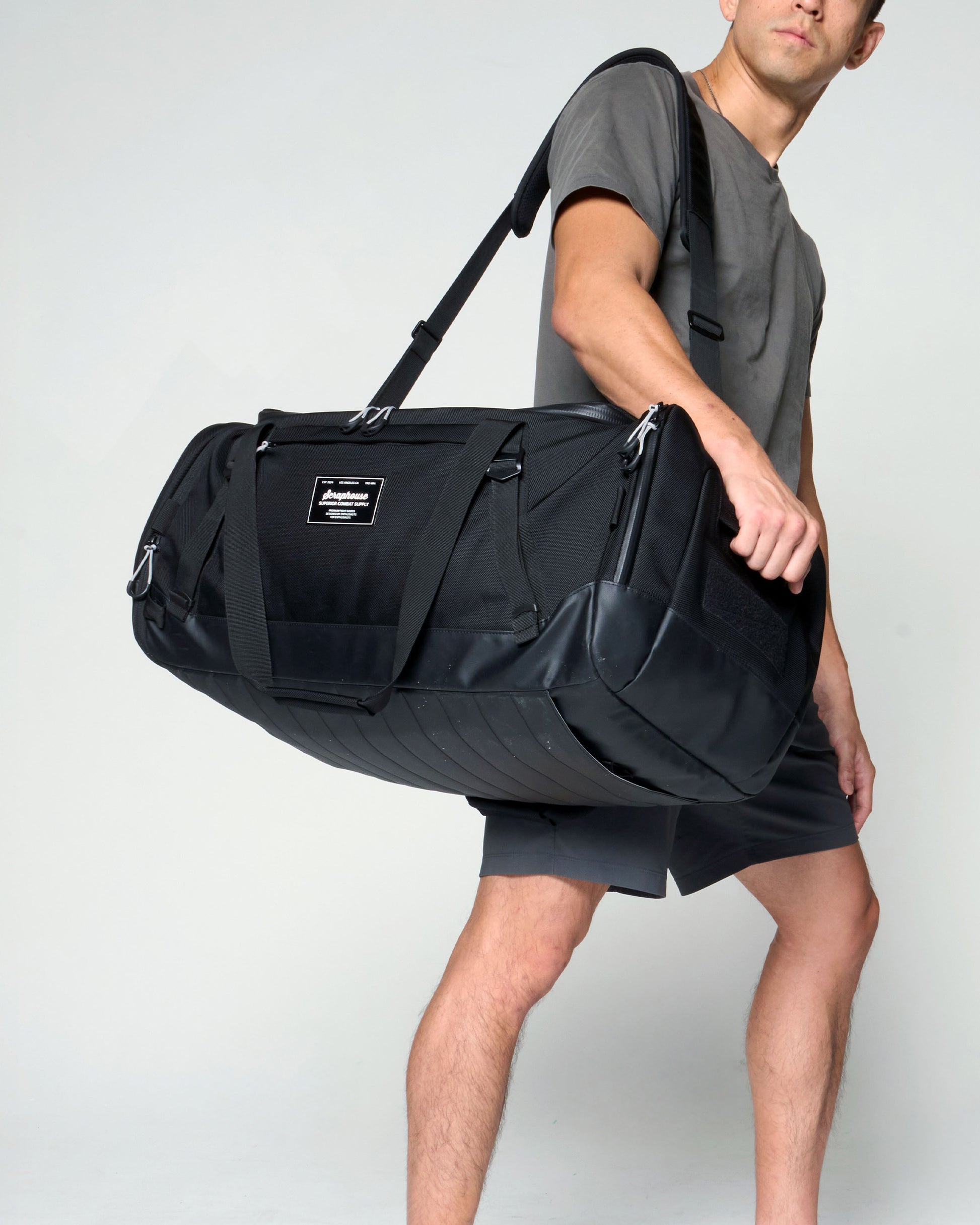 Athlete carrying the Scuffle Duffle on its padded shoulder sling, front three-quarter view