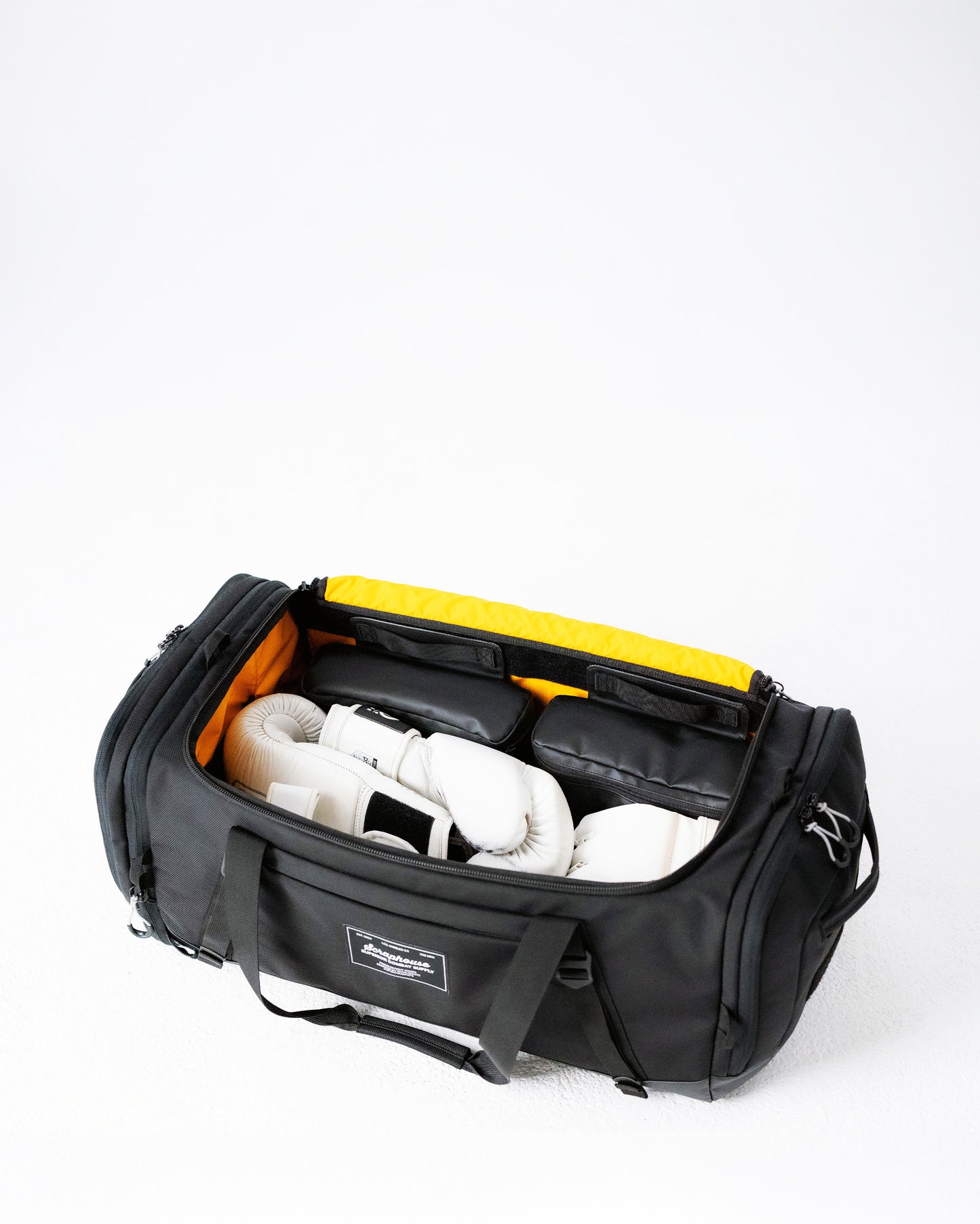 Scuffle Duffle open flat with white boxing gloves and modular saddleboxes against hi-vis yellow lining