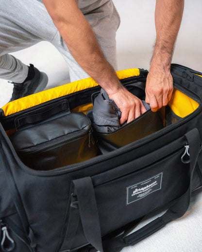 Athlete packing folded clothing into the Scuffle Duffle's adjustable interior dividers